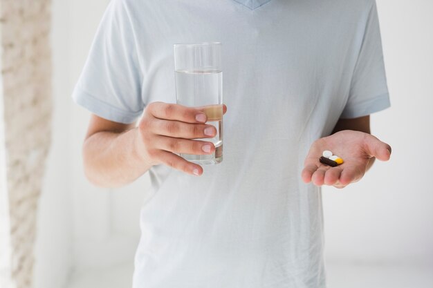 Hombre con pastillas y agua.