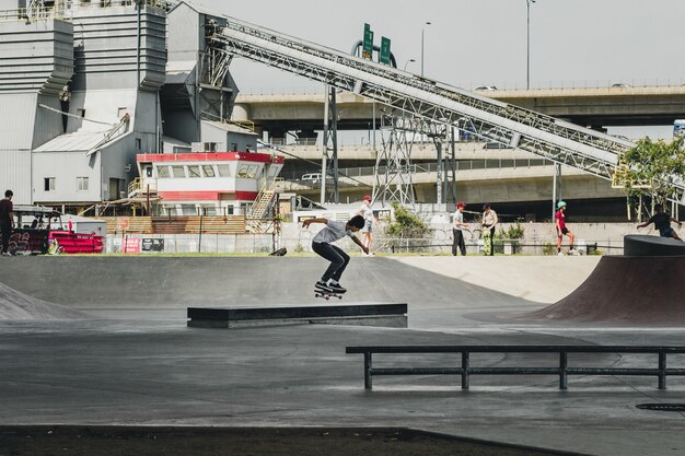 Hombre patinando en el skate park con edificio y personas