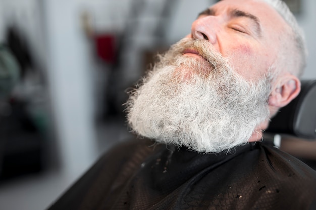 Hombre de pelo gris envejecido relajante en el salón