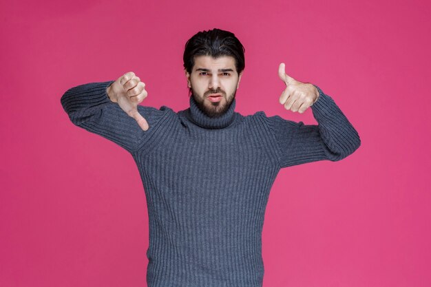 Hombre con pelo largo y barba haciendo el pulgar hacia arriba y hacia abajo.