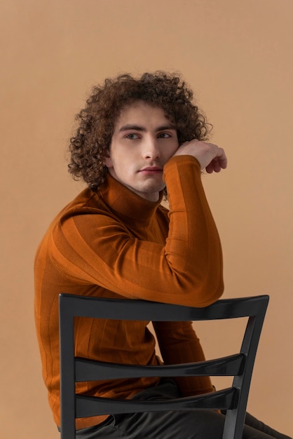 Hombre de pelo rizado con blusa marrón posando