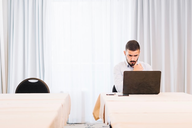 Hombre de pensamiento en la computadora portátil en la oficina