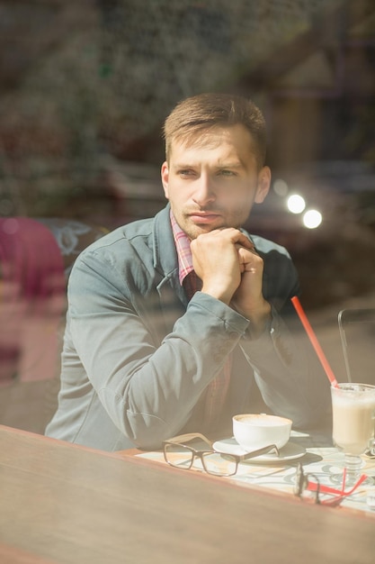 Hombre pensando en la organización de su horario de trabajo Lindo y serio joven mirando por la ventana