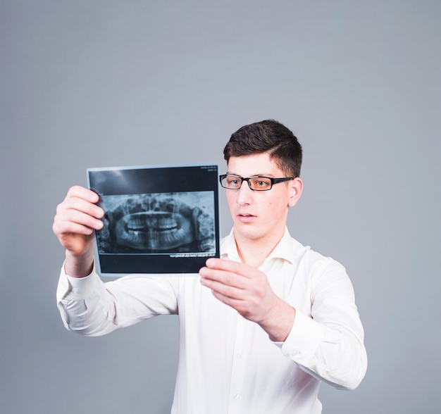 Foto gratuita hombre pensativo mirando la radiografía de los dientes