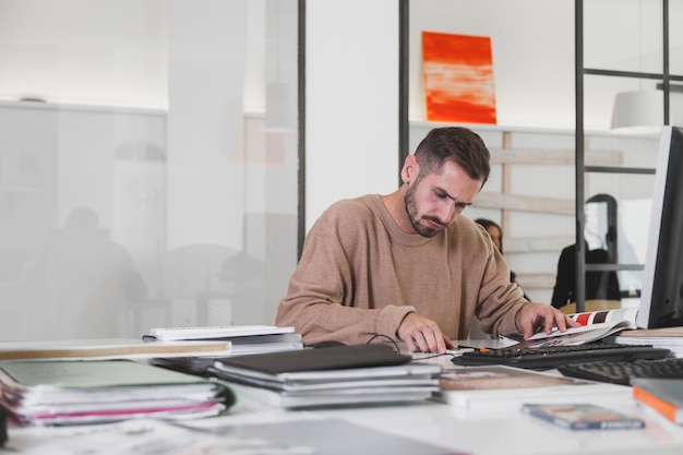 Foto gratuita hombre pensativo mirando la revista en la oficina