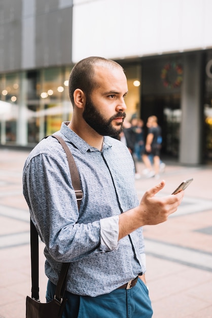 Hombre pensativo que usa el teléfono al aire libre