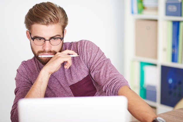 Hombre pensativo trabajando en equipo portátil