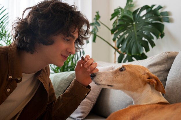 Foto gratuita hombre con perro galgo en casa en el sofá