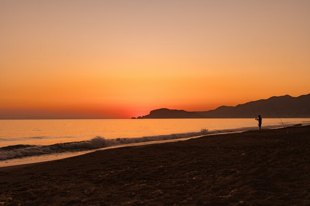 Hombre pescando en el mar al amanecer