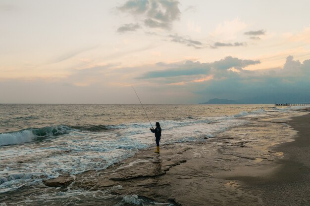 Hombre pescando en la orilla del mar