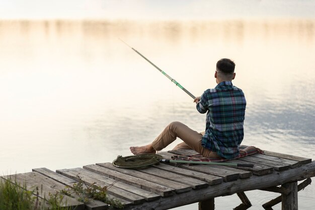 Hombre pescando por sí mismo full shot