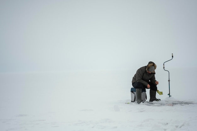 Hombre pescando solo afuera en invierno