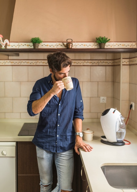 Hombre de pie en la cocina tomando café