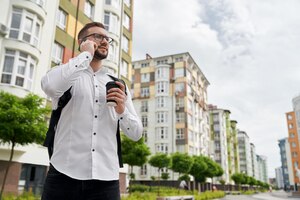 Foto gratuita hombre de pie hablando por teléfono mirando nuevos edificios