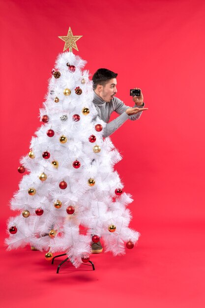 Foto gratuita un hombre está de pie junto al árbol de navidad.