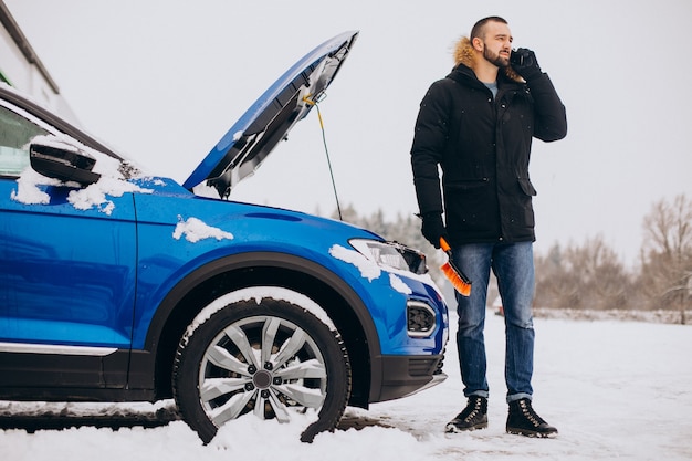 Hombre de pie junto al coche roto y pidiendo ayuda