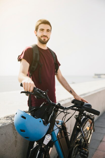 Hombre de pie junto a la bicicleta eléctrica y mirando a la cámara