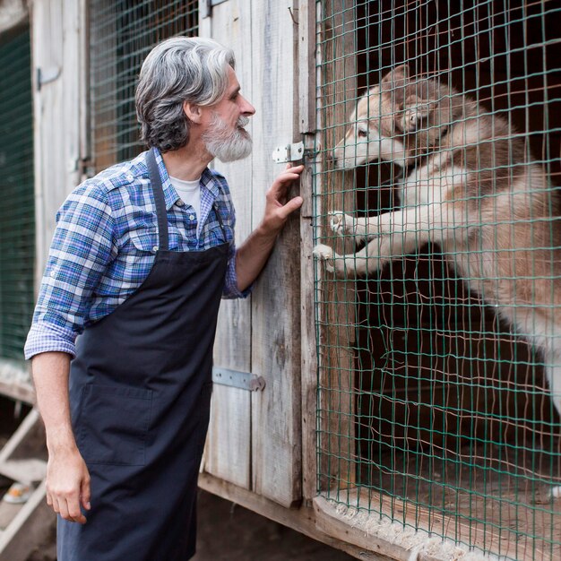 Hombre de pie junto a la jaula para perros