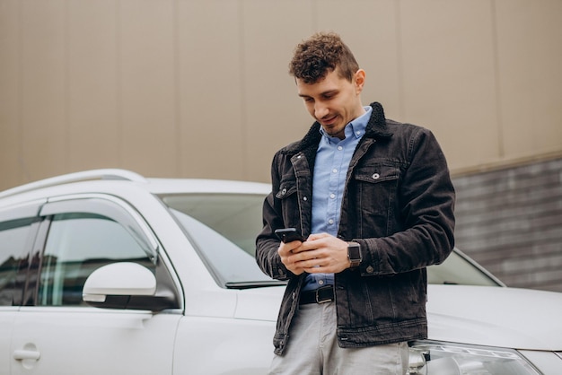 Hombre de pie junto a su coche y hablando por teléfono