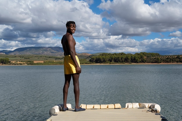 Foto gratuita hombre de pie junto a la vista lateral del lago