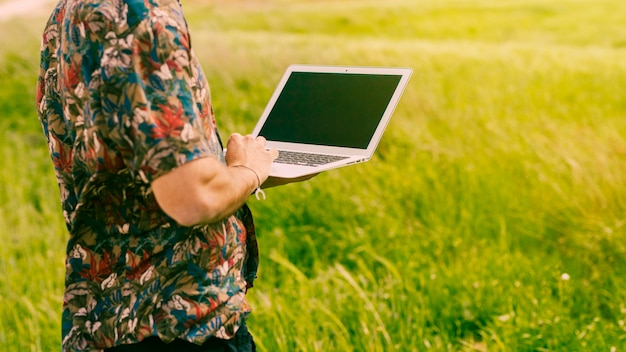 Foto gratuita hombre de pie con laptop en glade