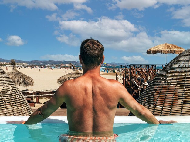 Hombre de pie en la piscina y disfrutando del verano