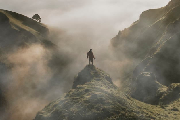 Foto gratuita hombre de pie sobre un acantilado con textura de superposición de niebla