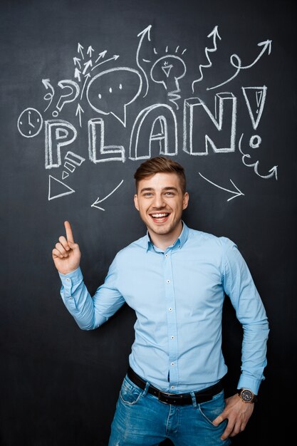 Hombre de pie sobre la pizarra con un punto de concepto de plan arriba