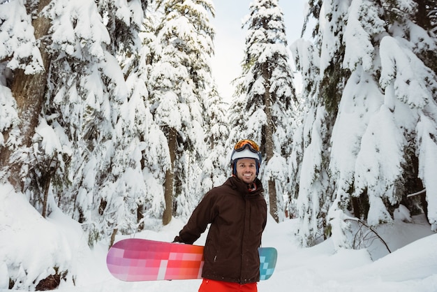 Hombre de pie y sosteniendo una tabla de snowboard