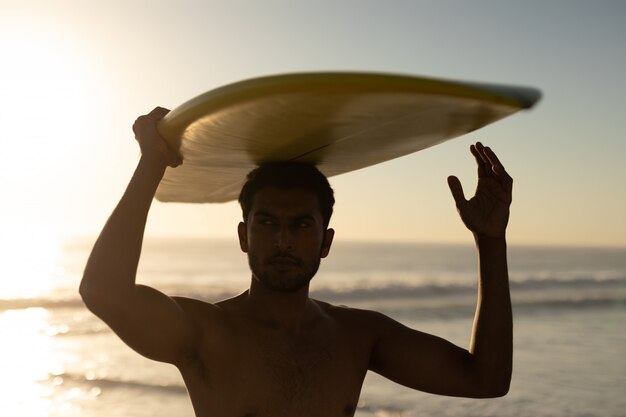 Hombre de pie con tabla de surf en la playa