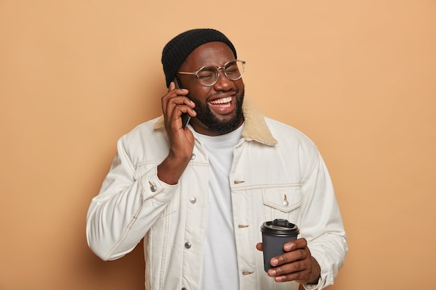 El hombre de piel oscura tiene una conversación telefónica divertida, se ríe durante la conversación telefónica