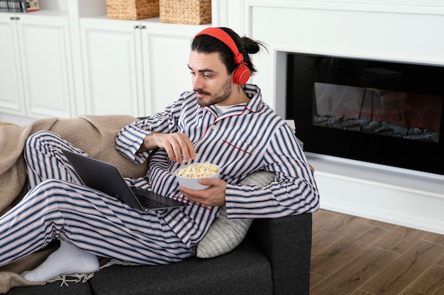 Hombre en pijama comiendo palomitas de maíz vista alta