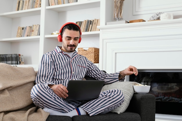 Hombre en pijama pasar tiempo divertido en la computadora portátil