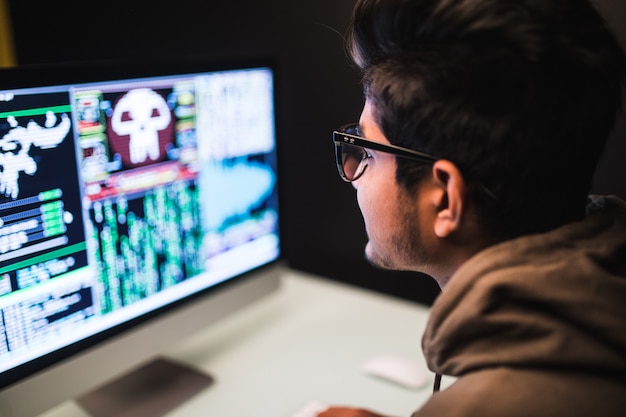 Hombre pirata informático indio usando computadoras para robar datos en el escritorio