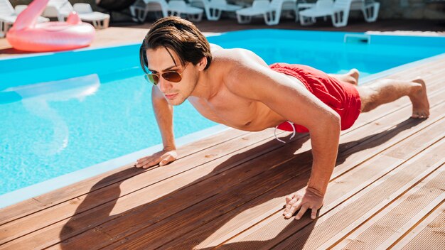 Hombre en la piscina haciendo flexiones.