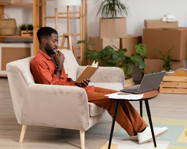 Hombre planeando redecorar casa usando laptop y libro
