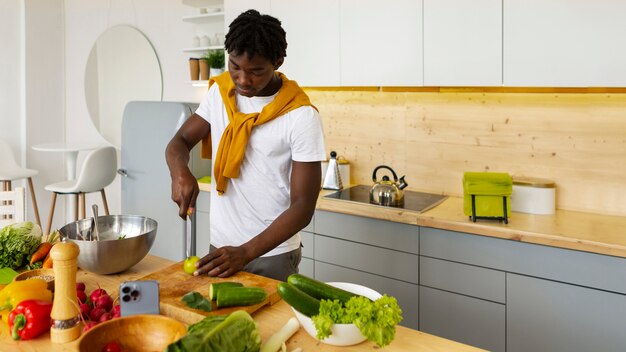 Hombre de plano medio cocinando con teléfono inteligente