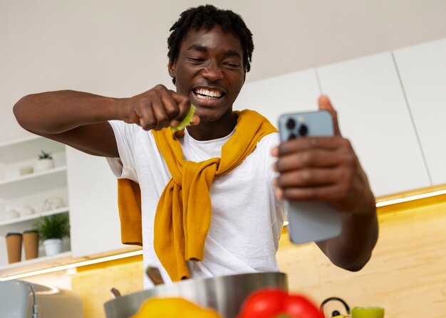 Hombre de plano medio cocinando con teléfono inteligente