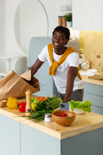 Foto gratuita hombre de plano medio cocinando con teléfono inteligente