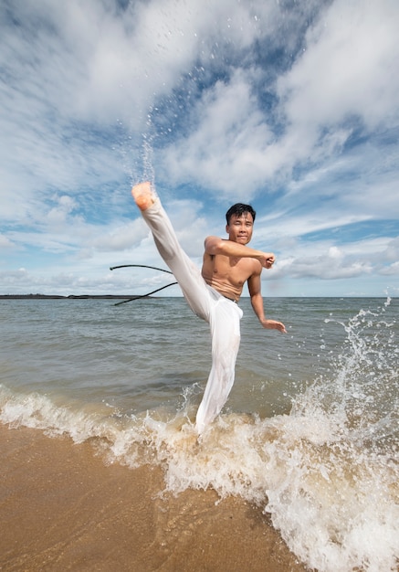 Hombre en la playa practicando capoeira solo