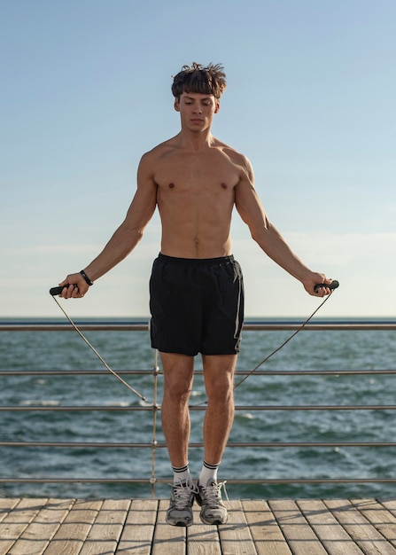 Foto gratuita hombre en la playa saltando la cuerda