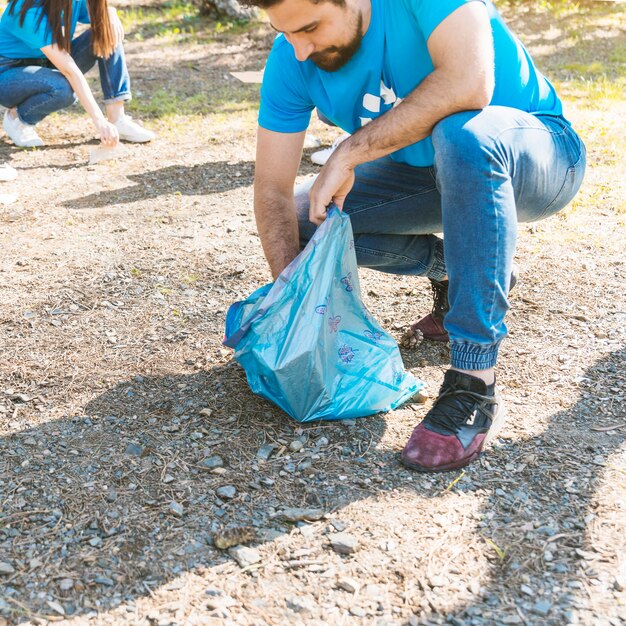 Hombre plegable basura en bolsa de basura