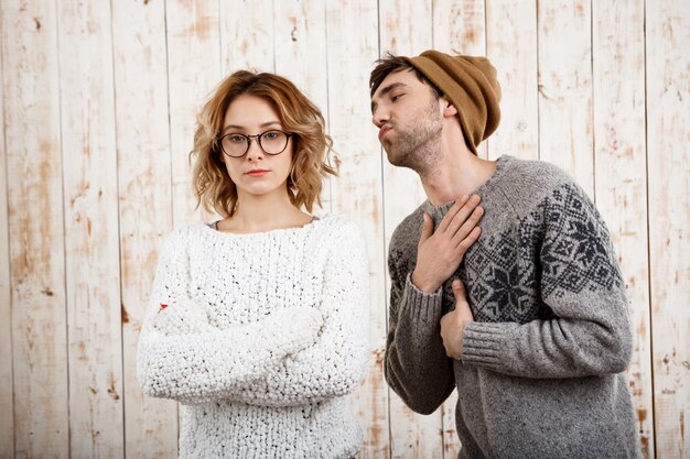 El hombre pone nervioso a su novia con los brazos cruzados sobre la pared de madera