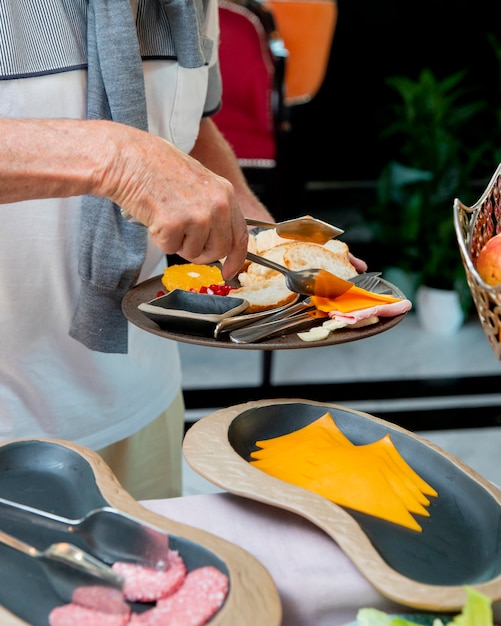 Foto gratuita el hombre pone queso en lonchas en su plato