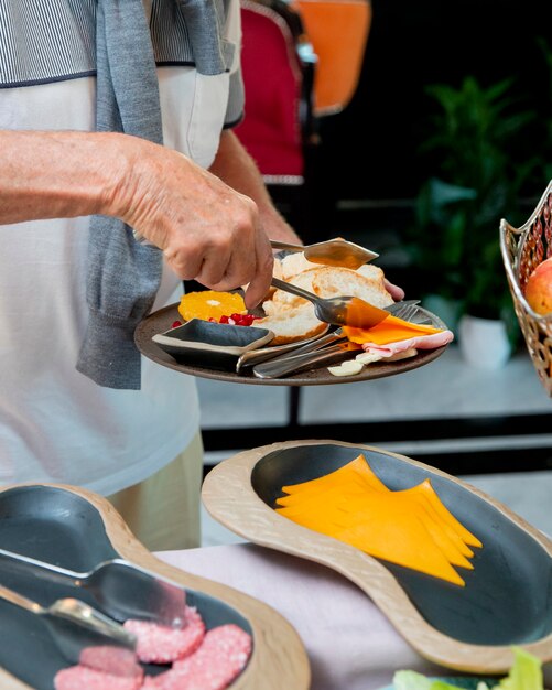 El hombre pone queso en lonchas en su plato