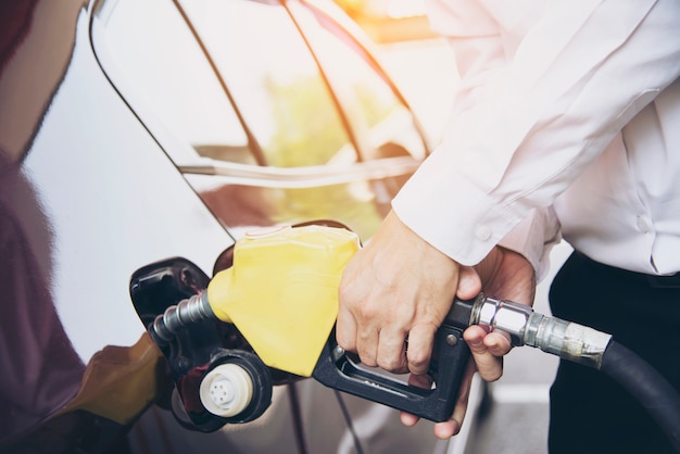 Hombre poniendo combustible de gasolina en su automóvil en una gasolinera de la bomba