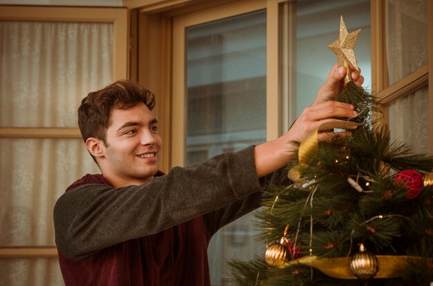 Hombre, poniendo, estrella, en, árbol de navidad, cima