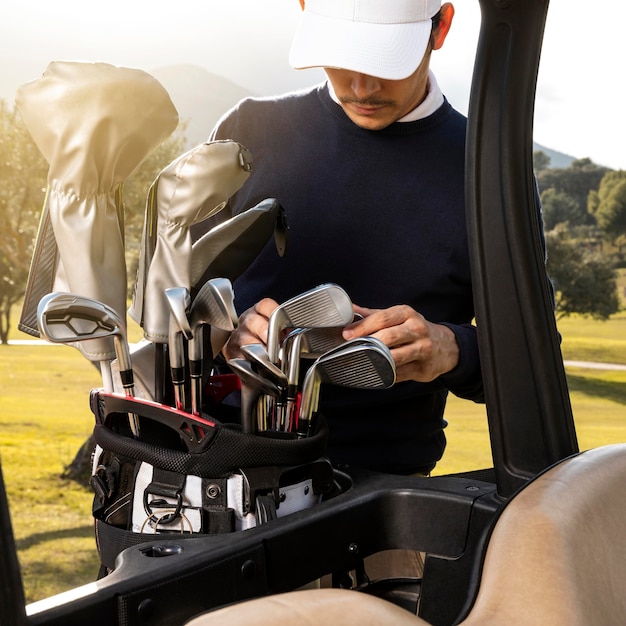 Foto gratuita hombre poniendo palos en carrito de golf