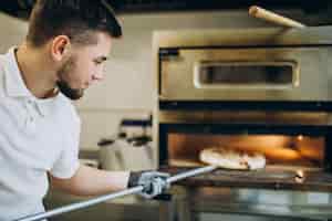 Foto gratuita hombre poniendo pizza en el horno en la pizzería
