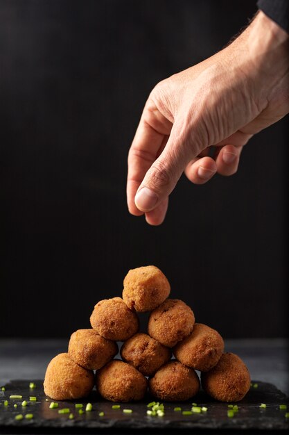 Hombre poniendo sal en croquetas con perejil